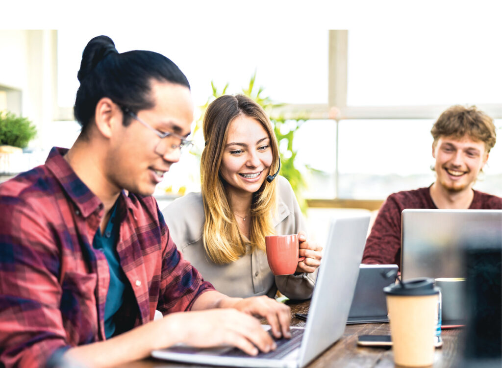 Young employee coworkers sharing content on laptop